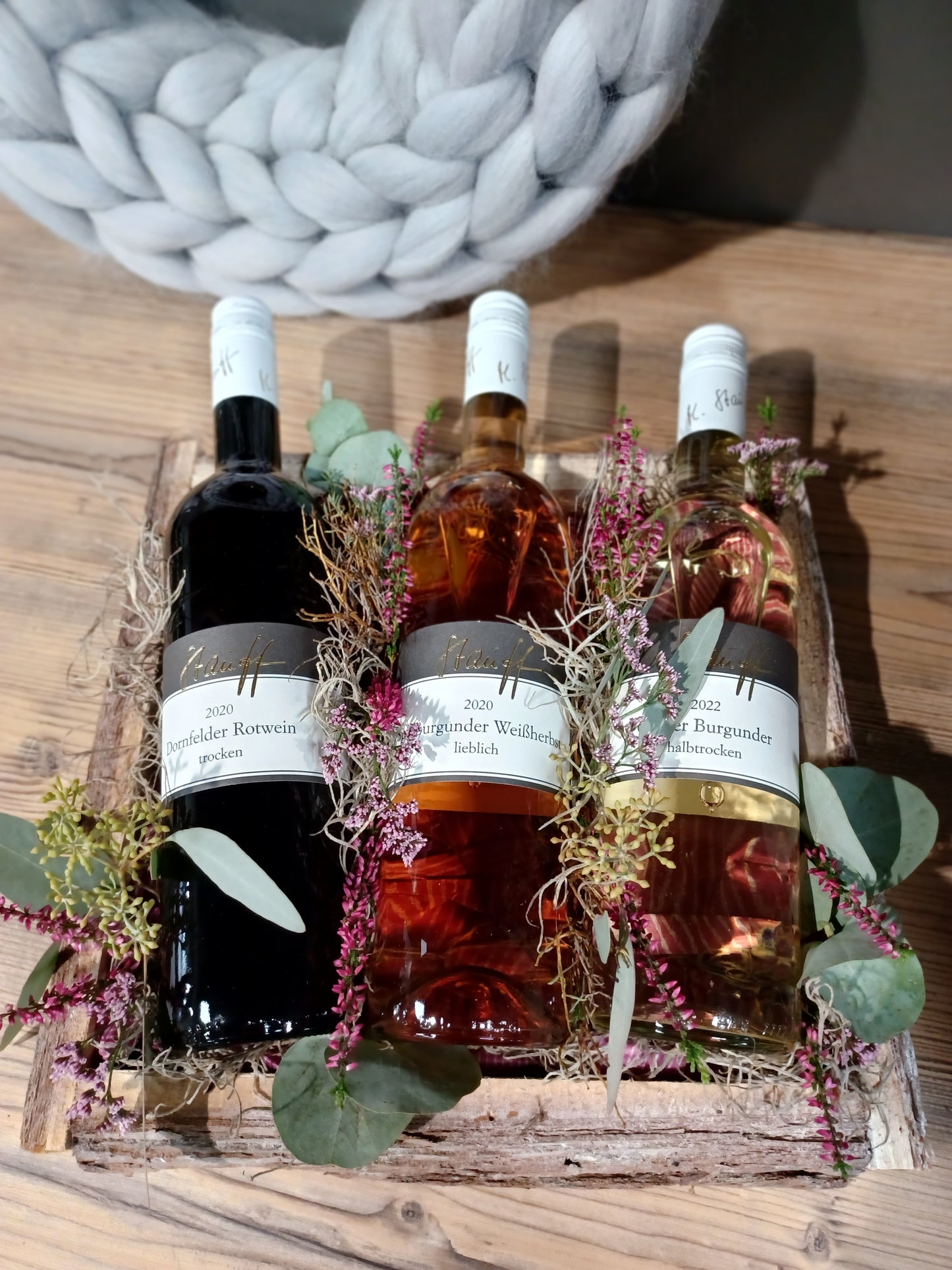 3 Weinflaschen dekorativ verpackt auf Holztablett